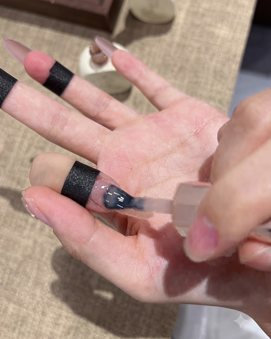 Un pinceau à ongles appliquant du gel œil-de-chat violet sur le bout dun ongle pour un effet ombré.