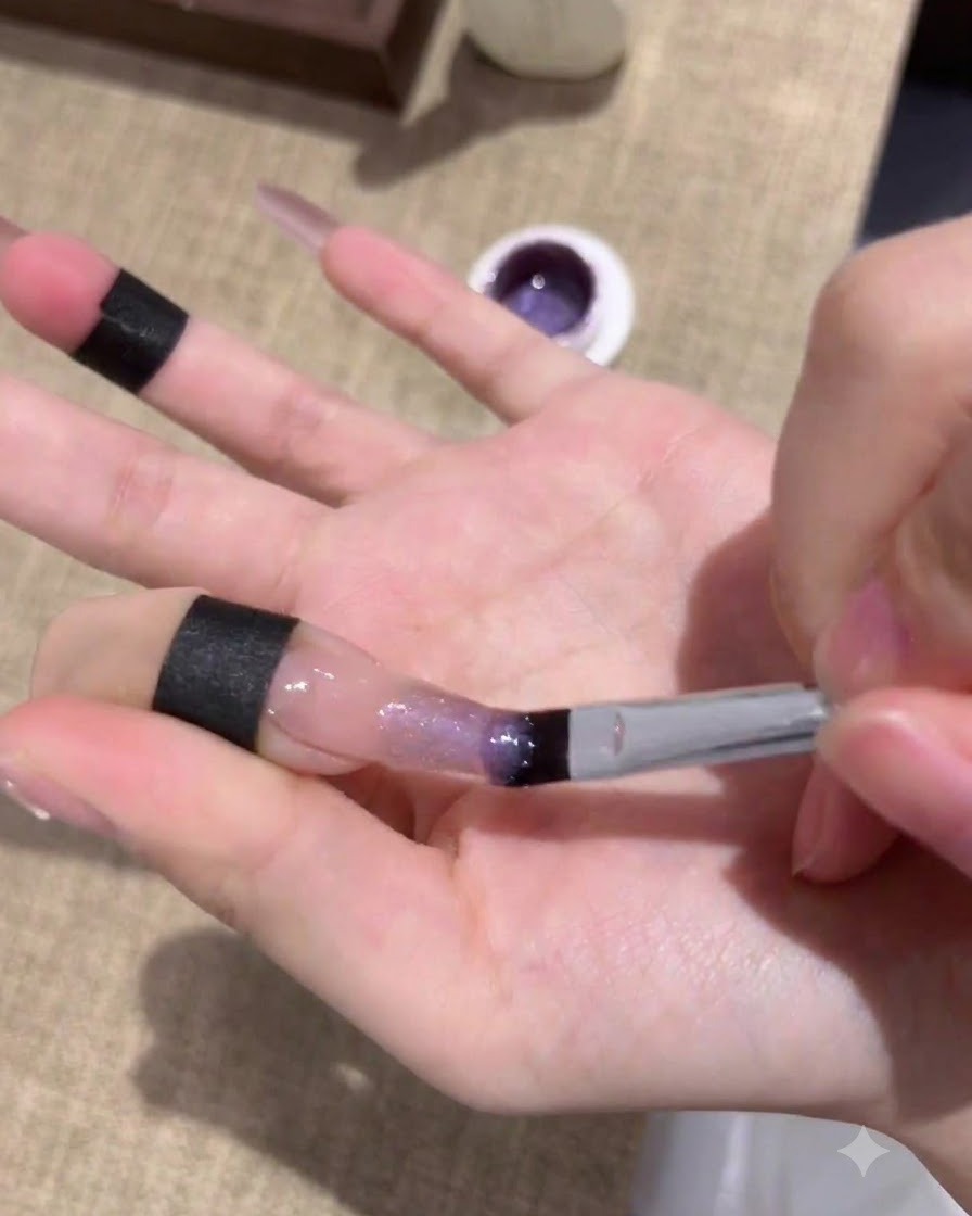 Ongles en train de catalyser sous une lampe UV/LED après lapplication de la première couche de gel œil-de-chat violet.