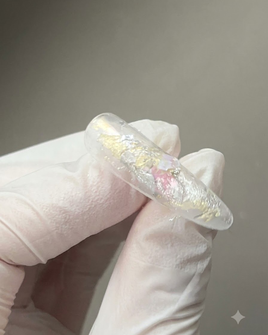 Un outil aimanté tenu de près au-dessus dun ongle enduit de gel brillant pour façonner les particules magnétiques réfléchissantes œil de chat.
