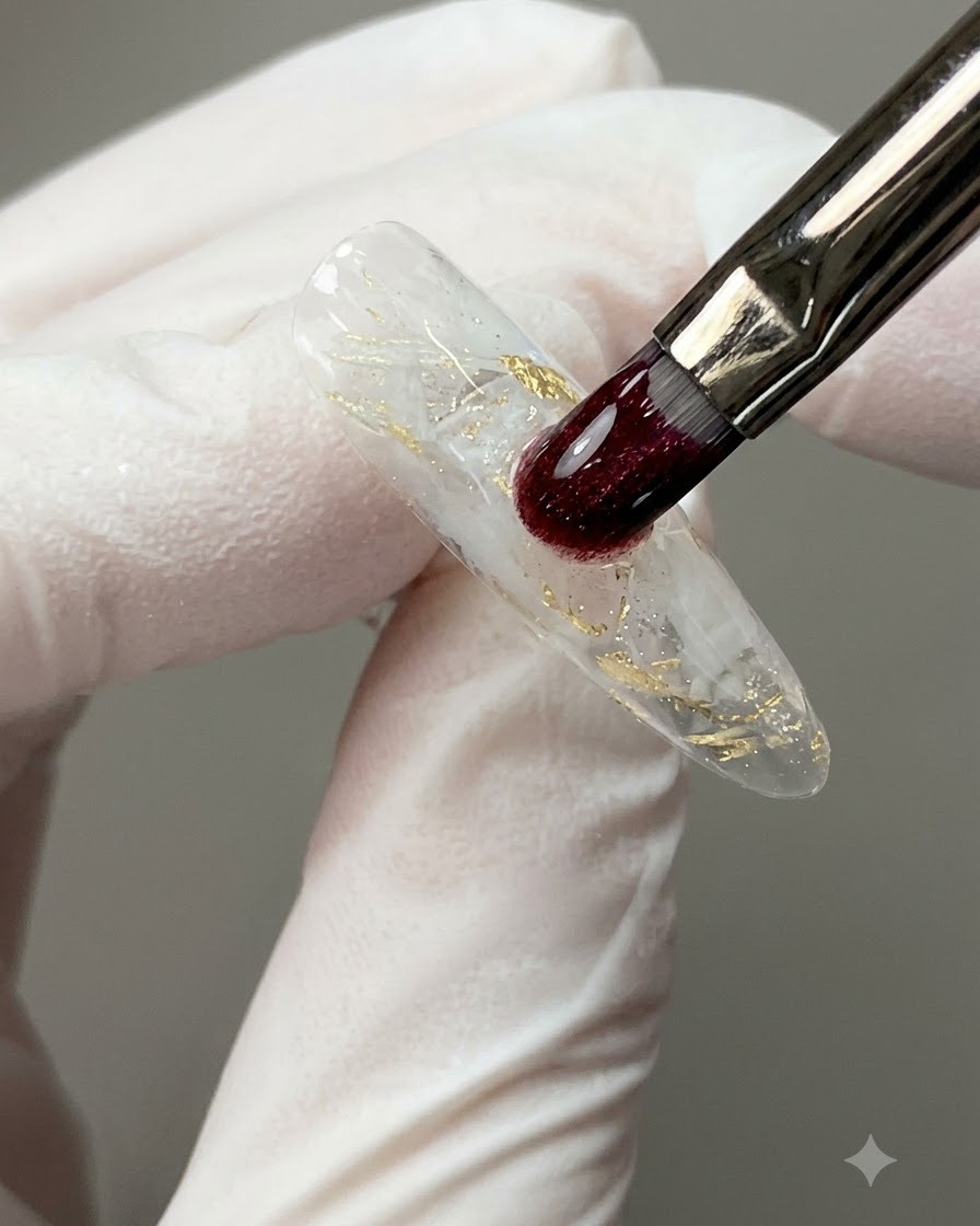 Un pinceau à ongles appliquant une goutte transparente autonivelante de gel de construction sur une surface dongle décorée.