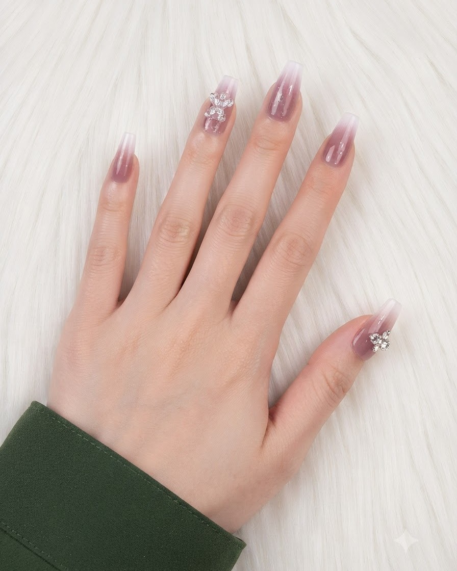 Une main avec des ongles dégradés finis et des charms placés sur lannulaire et le pouce.