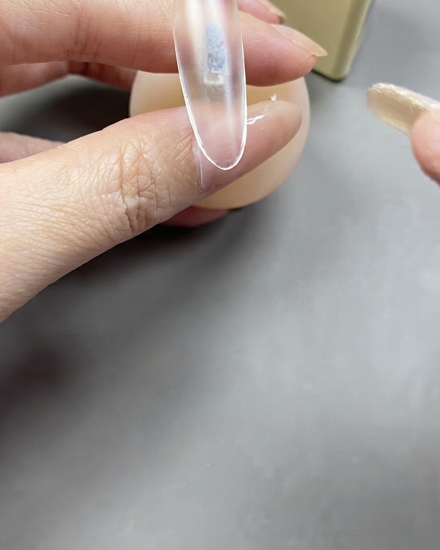 Un pinceau appliquant une couche transparente de gel de base sur une extension dongle transparente.