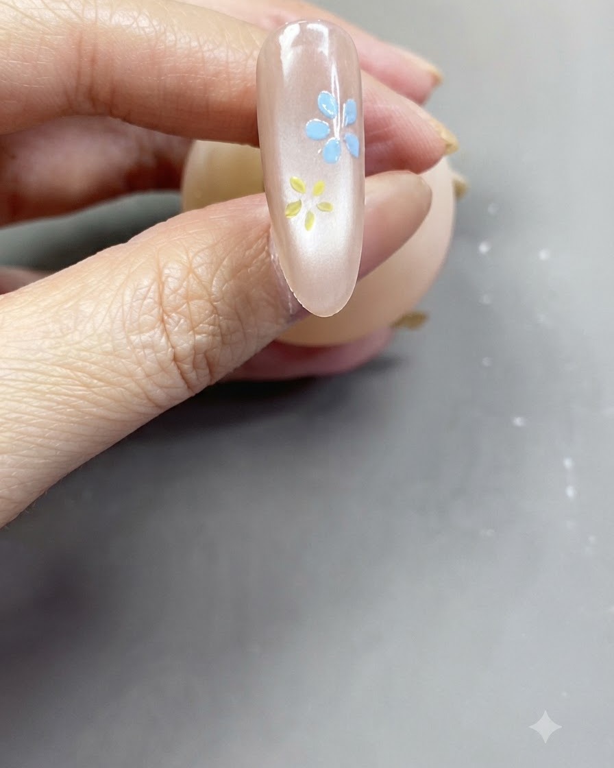Vue rapprochée dune fleur rose tendre terminée peinte sur un ongle nude rosé brillant.