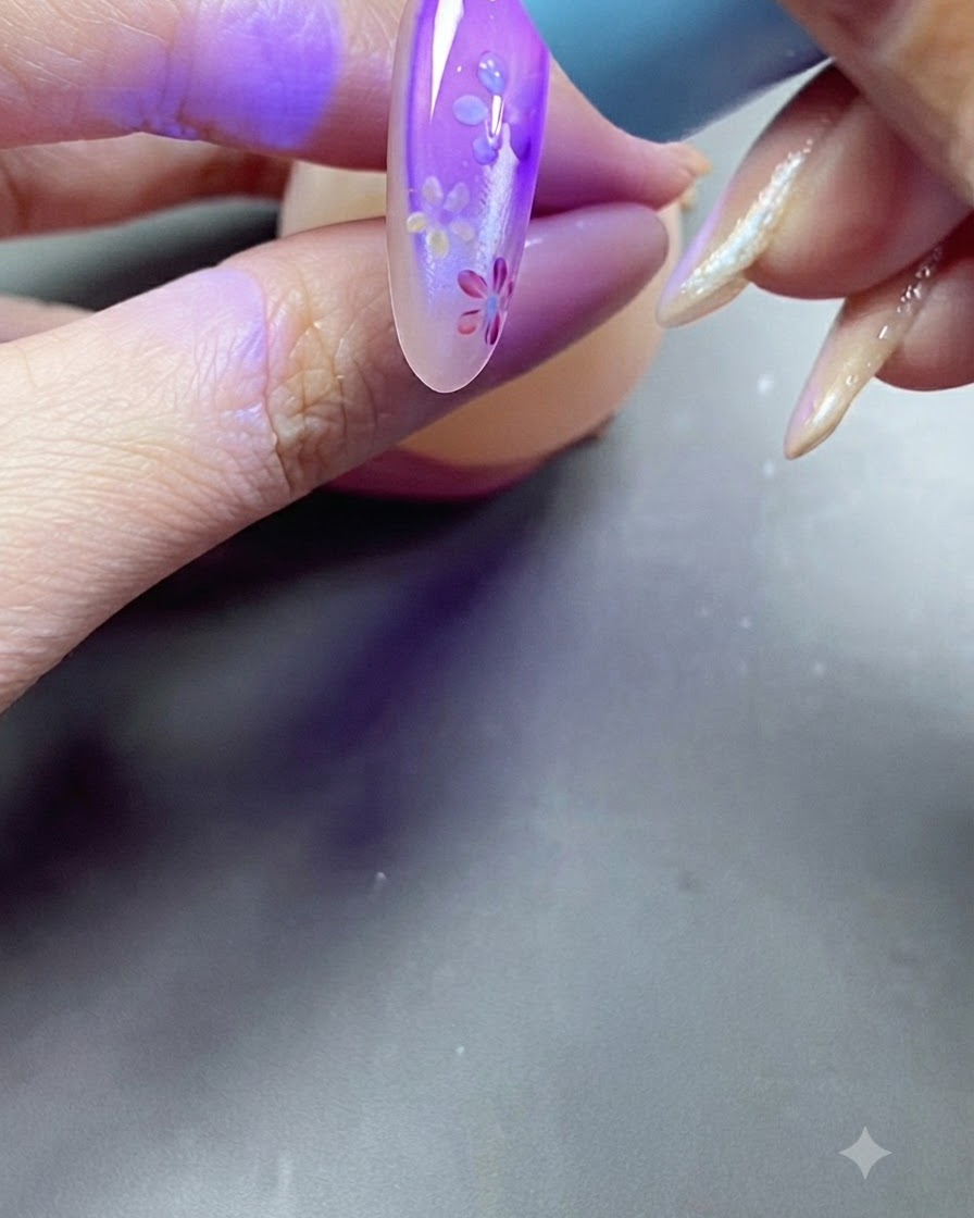 Une main plaçant un ongle sous la lumière violette dune lampe UV pendant le processus de catalyse.