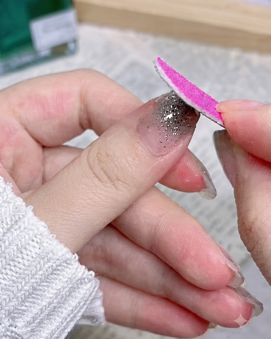 Une lime à ongles rose se déplaçant vers le bas le long du bord dun ongle pour éliminer le matériau de wrap excédentaire.