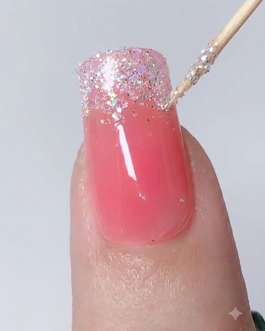 Un outil de détail tapotant et étirant des paillettes argentées vers le bas pour former un ombré sur un ongle.