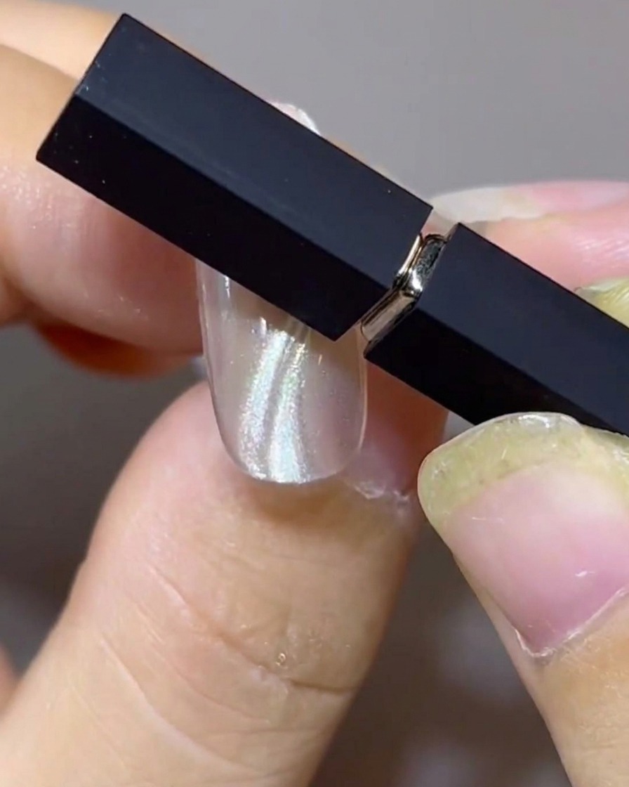 Deux aimants positionnés en biais au-dessus dun ongle pour façonner des doubles bandes cat-eye flottantes et parallèles.