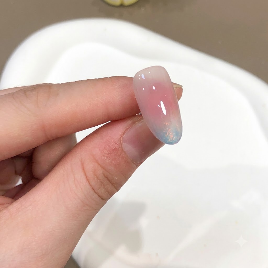 Gros plan dun ongle affichant un effet de poudre aurora rose et bleue avec une finition ultra brillante.