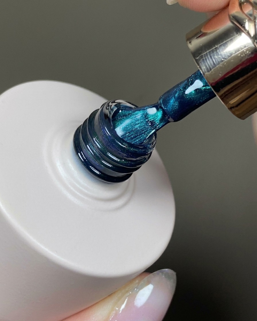 Un pinceau à ongles appliquant une fine couche de gel cat eye sur un ongle.