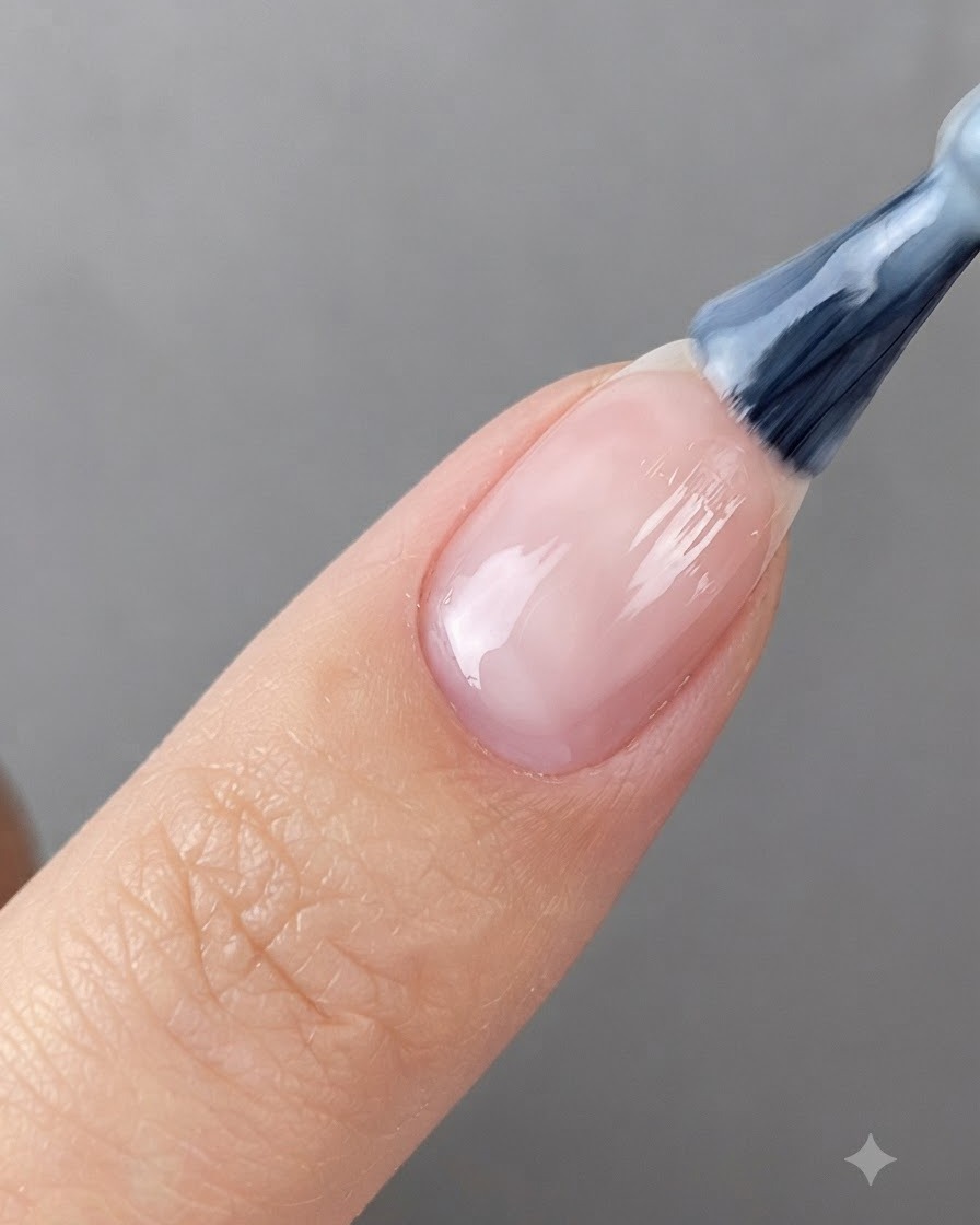 Un pinceau à ongle appliquant du gel blanc translucide sur un ongle préparé.