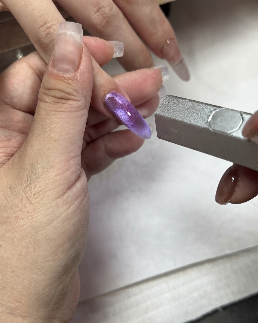 Un bâtonnet aimanté utilisé sur un bloc de couleur violette effet œil de chat appliqué sur un index.