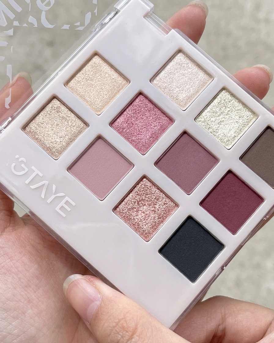 Un outil en silicone prélevant du gel rose pêche dans une palette à compartiments multiples pour fards et gels.
