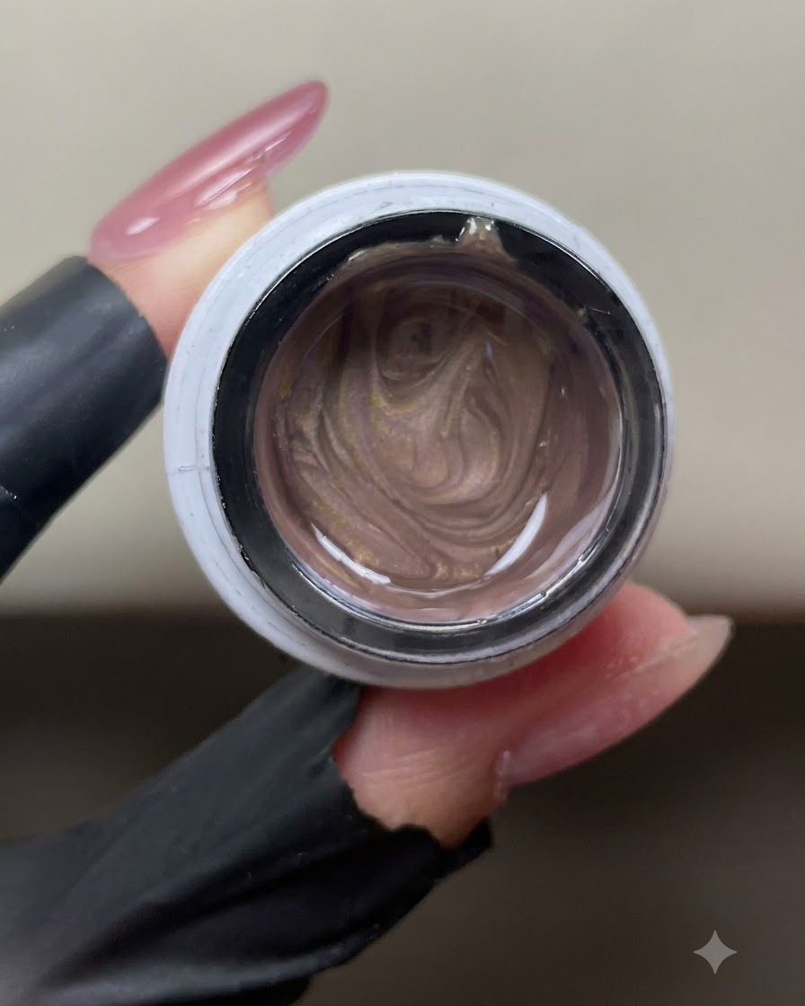 Un pot ouvert de gel œil de chat rose-doré scintillant montrant des particules magnétiques métalliques tourbillonnantes à lintérieur.