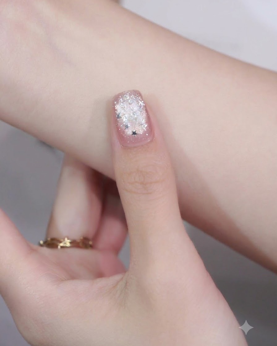 Gros plan dun ongle manucuré avec une pièce de paillette en forme détoile placée sur le bout par-dessus un détail de nail art en frange.