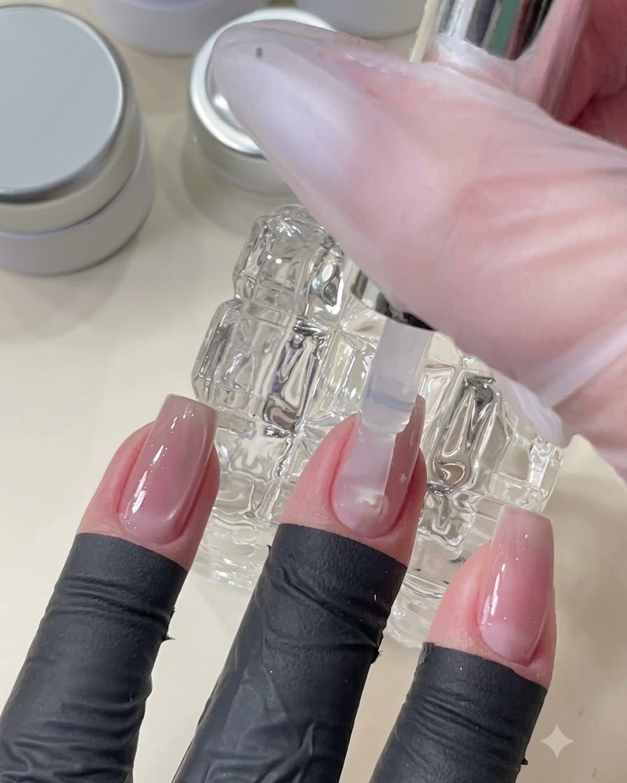 Un pinceau appliquant un gel top coat transparent pour lisser et niveler la surface de longle sur le nail art incrusté.
