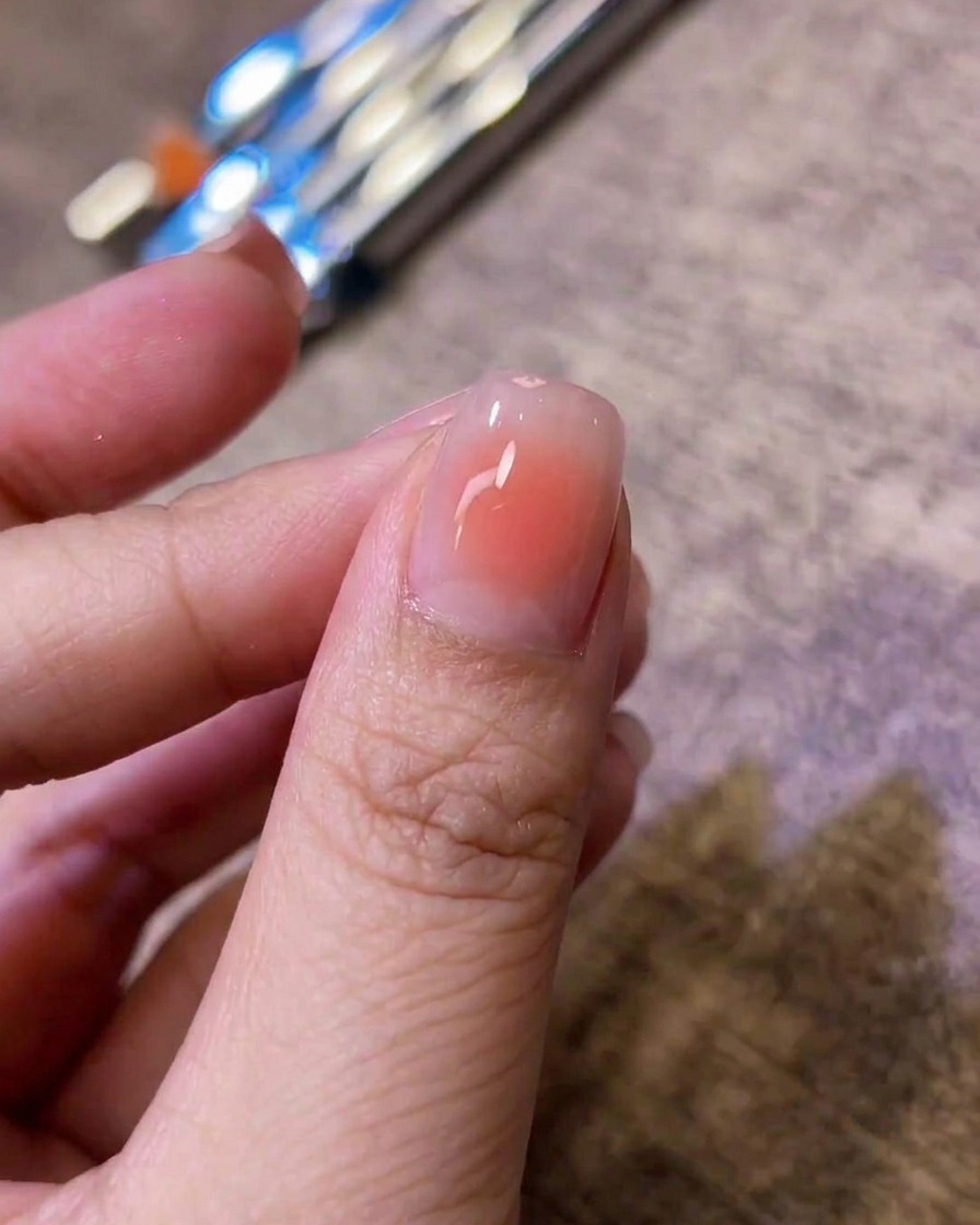 Gros plan dun ongle brillant présentant un centre rose blush délicatement estompé sur une base nude.