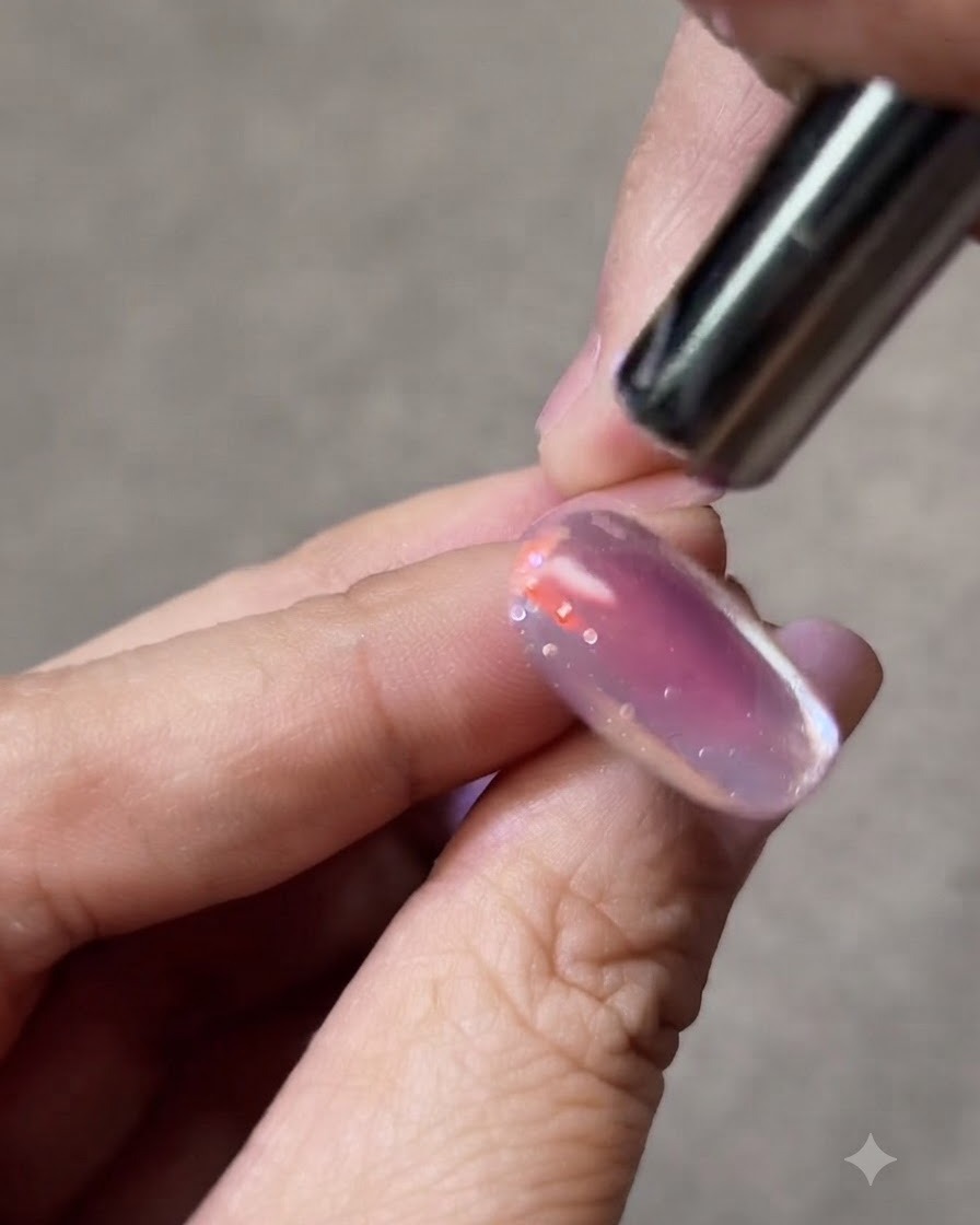 Un petit aimant tenu près dun ongle en gel cat-eye pour façonner la bande de lumière brillante.