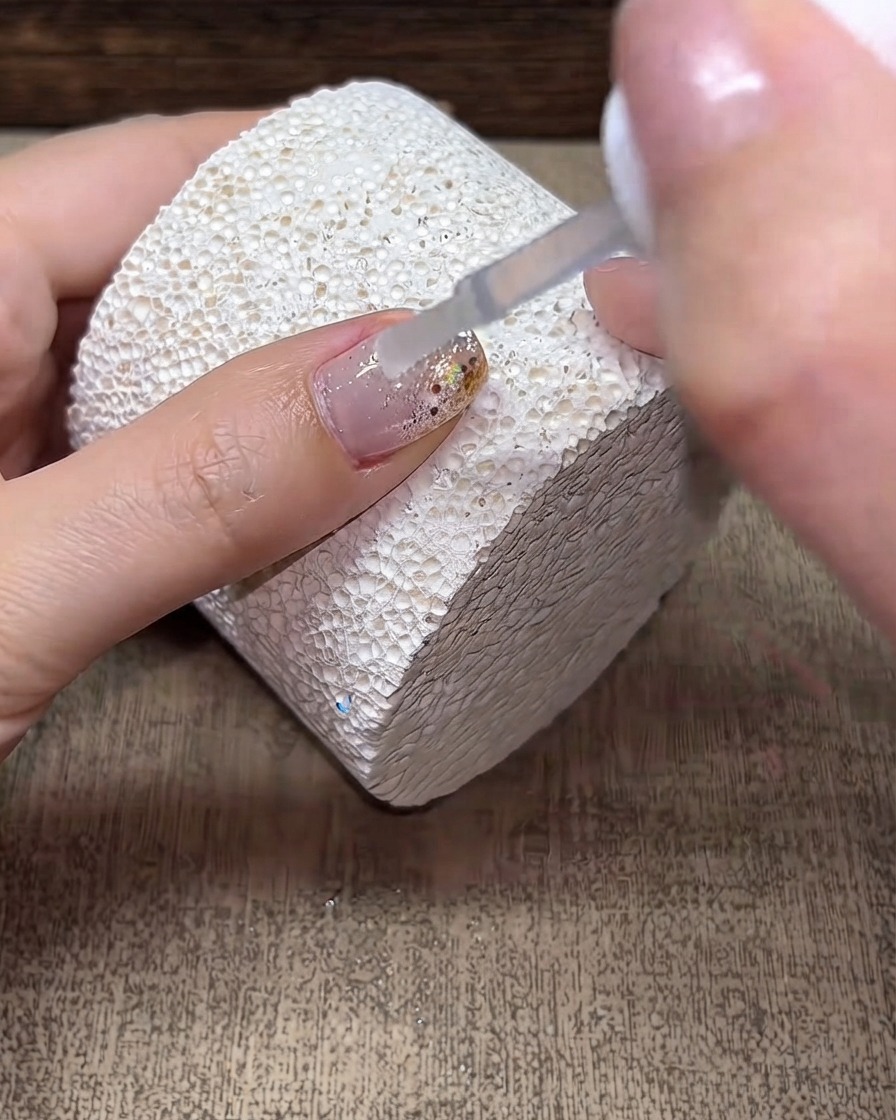 Un pinceau appliquant une couche transparente de gel de construction sur une surface dongle décorée.