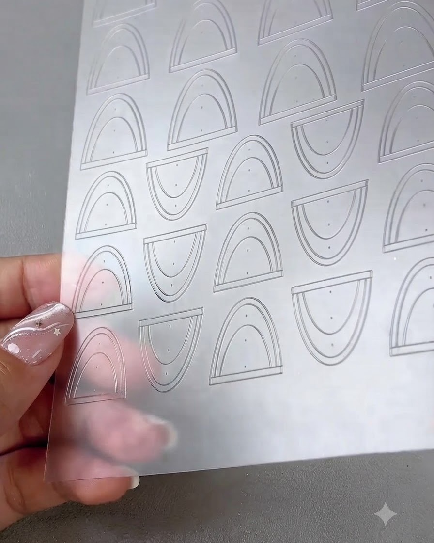 Vue rapprochée dune feuille transparente contenant plusieurs autocollants incurvés pour french tip et nail art.