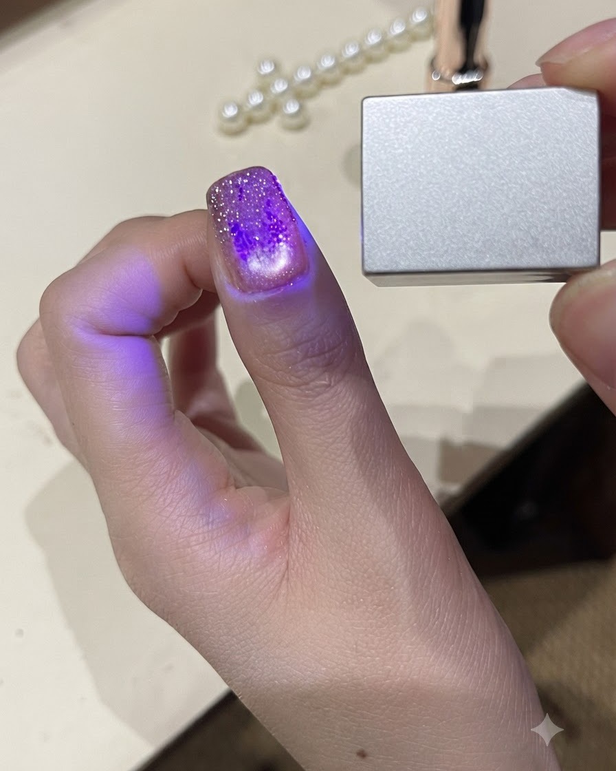 Vue rapprochée dun pouce sous une petite lampe UV LED portable catalysant le vernis gel.