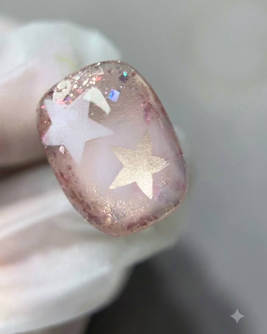 Un pinceau estompant délicatement la limite intérieure du gel pailleté rose sur longle.