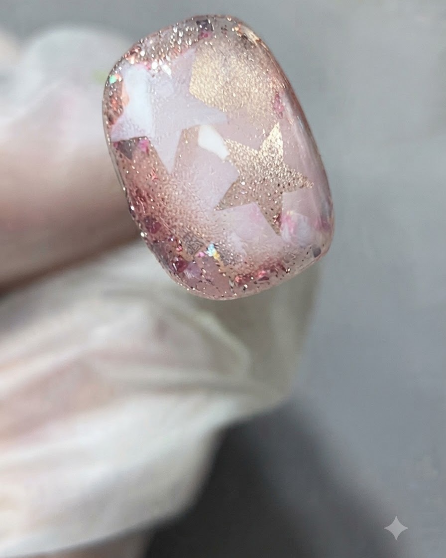 Une paire de brucelles ou des doigts gantés décollant délicatement un pochoir étoile dun nail art catalysé.