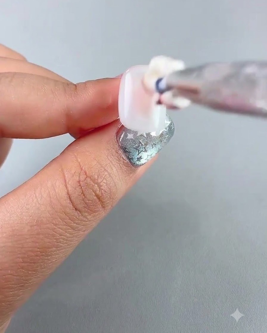 Vue détaillée dun pinceau appliquant un gel tapotant rosé au centre dun ongle.