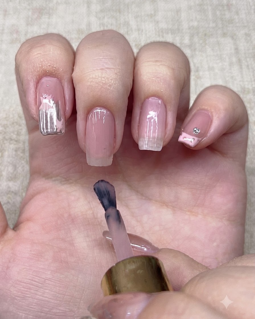 Un pinceau à vernis appliquant une couleur de base nude sur un onglet.
