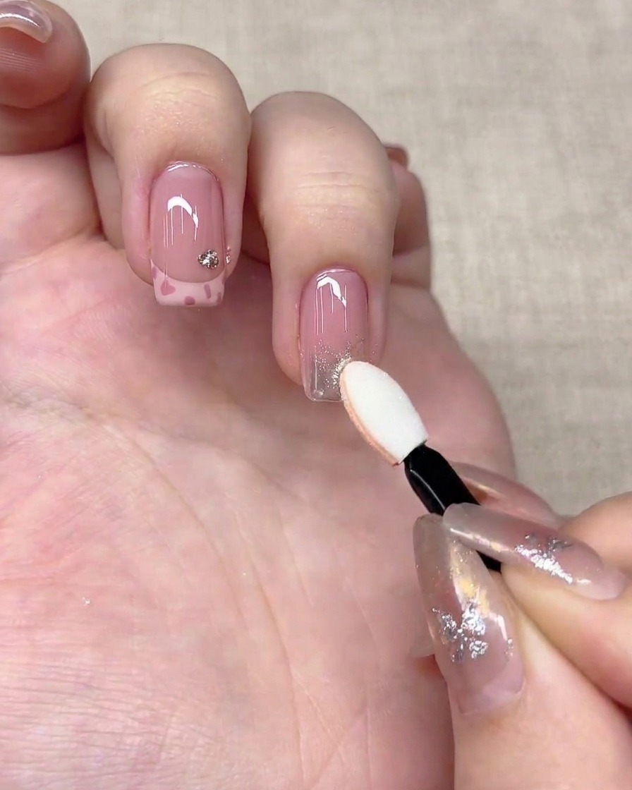 Un applicateur éponge à paupières pressant de la poudre chrome argentée sur le bout dun ongle.