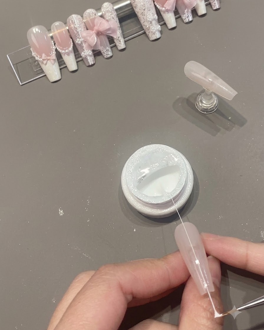 Un brin fin de gel spider blanc étiré au-dessus de la surface de longle et dun pot ouvert.