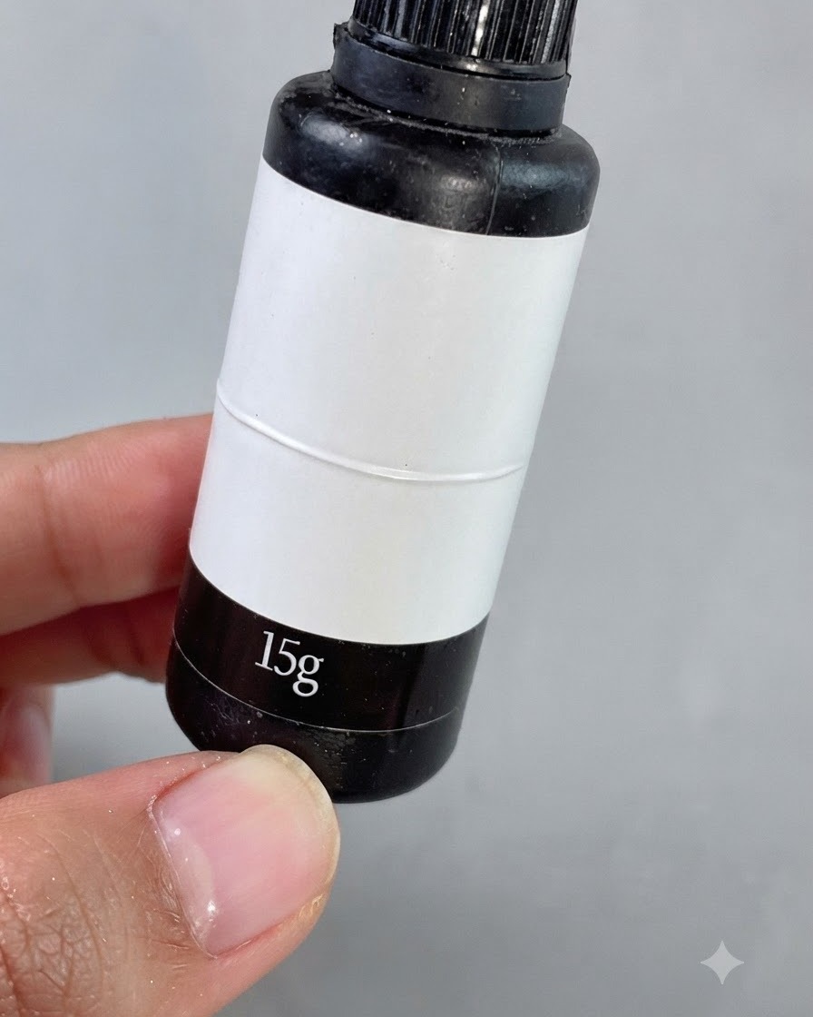 Un pinceau de détail fin appliquant un gel de comblement transparent autour de petits strass carrés sur un ongle manucuré.