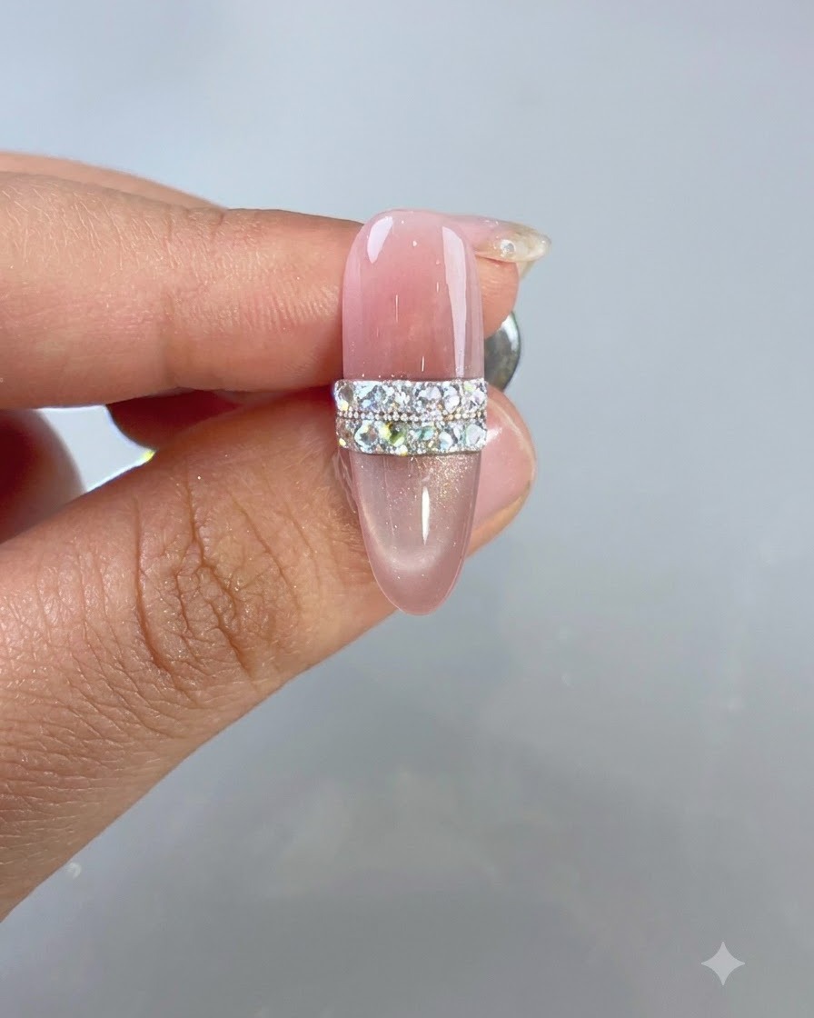 Un design dongle cat-eye rose terminé doté dun motif de bague en strass et perles sous un éclairage de studio.