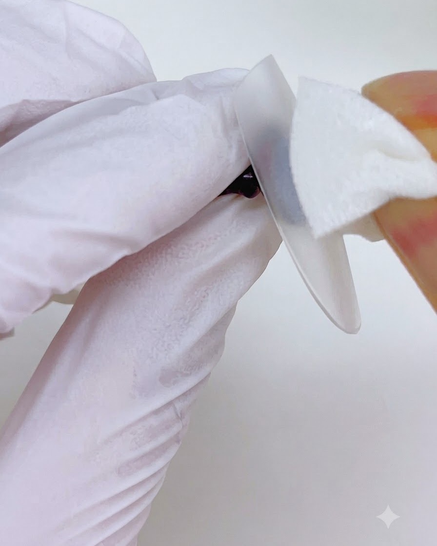 Essuyage de la surface dun onglet avec un pad nettoyant sans peluche pendant le processus dapplication.