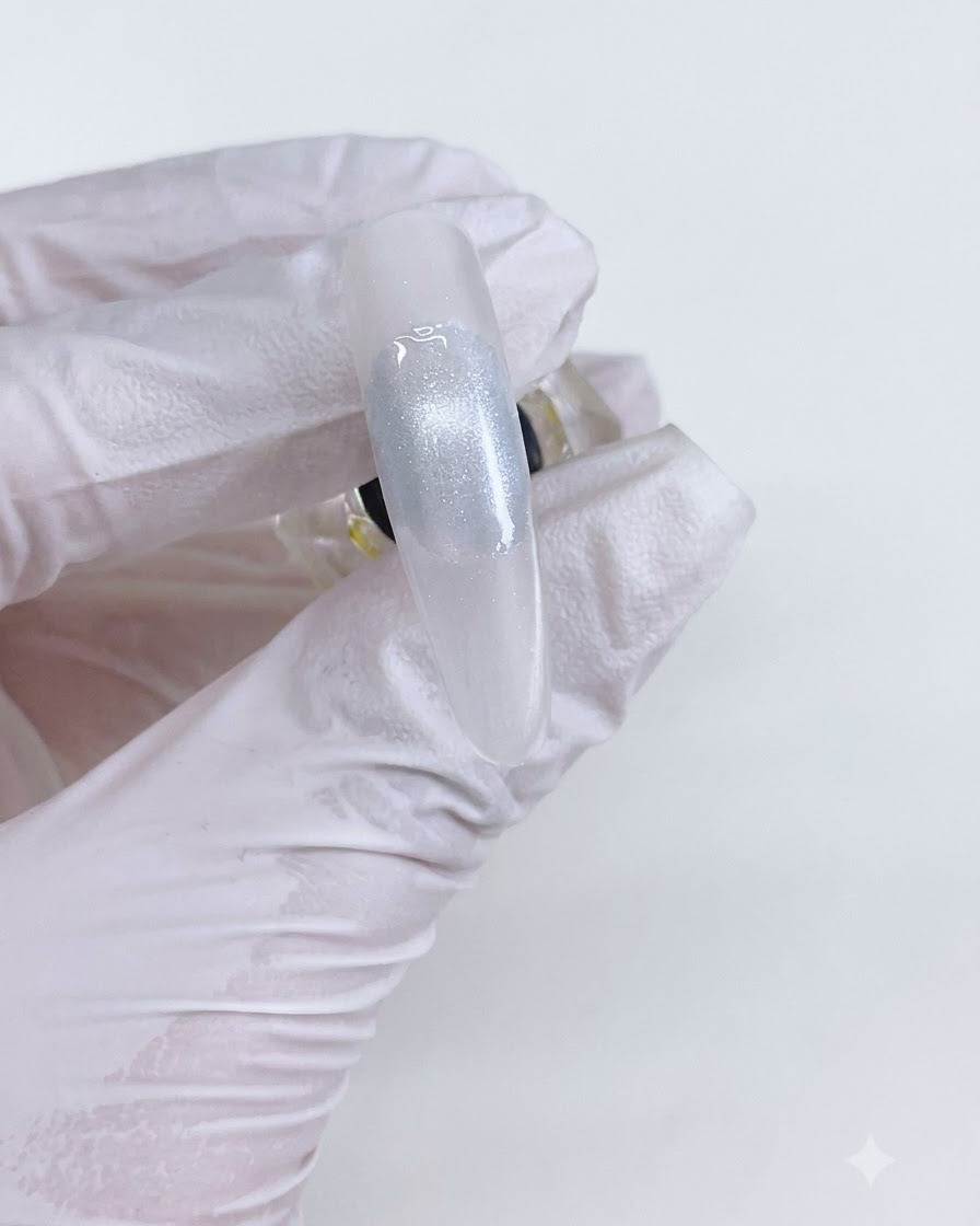 Une perle en gel cat-eye finie sur un ongle après catalysation sous une lampe.