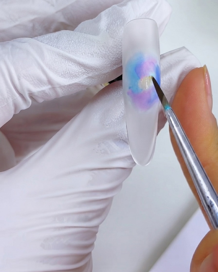 Un pinceau fin plaçant une touche dencre orange au milieu du motif blooming aquarelle.