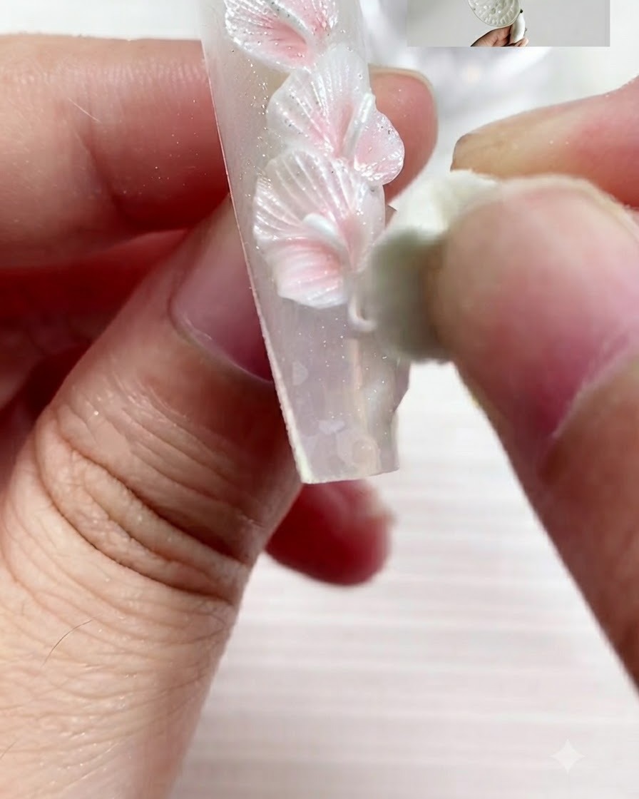 Un outil de modelage pressant et façonnant un morceau de gel en un pétale de lys calla aplati.