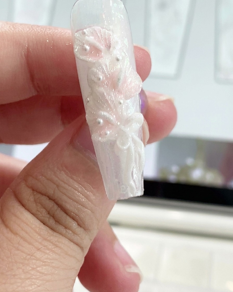 Un outil en silicone façonnant un nœud ruban en gel sur un ongle décoré.