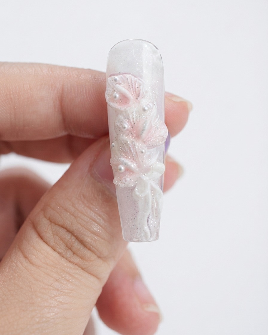 Une éponge de maquillage tamponnant du gel rose clair sur des pétales de lys calla blancs sculptés.