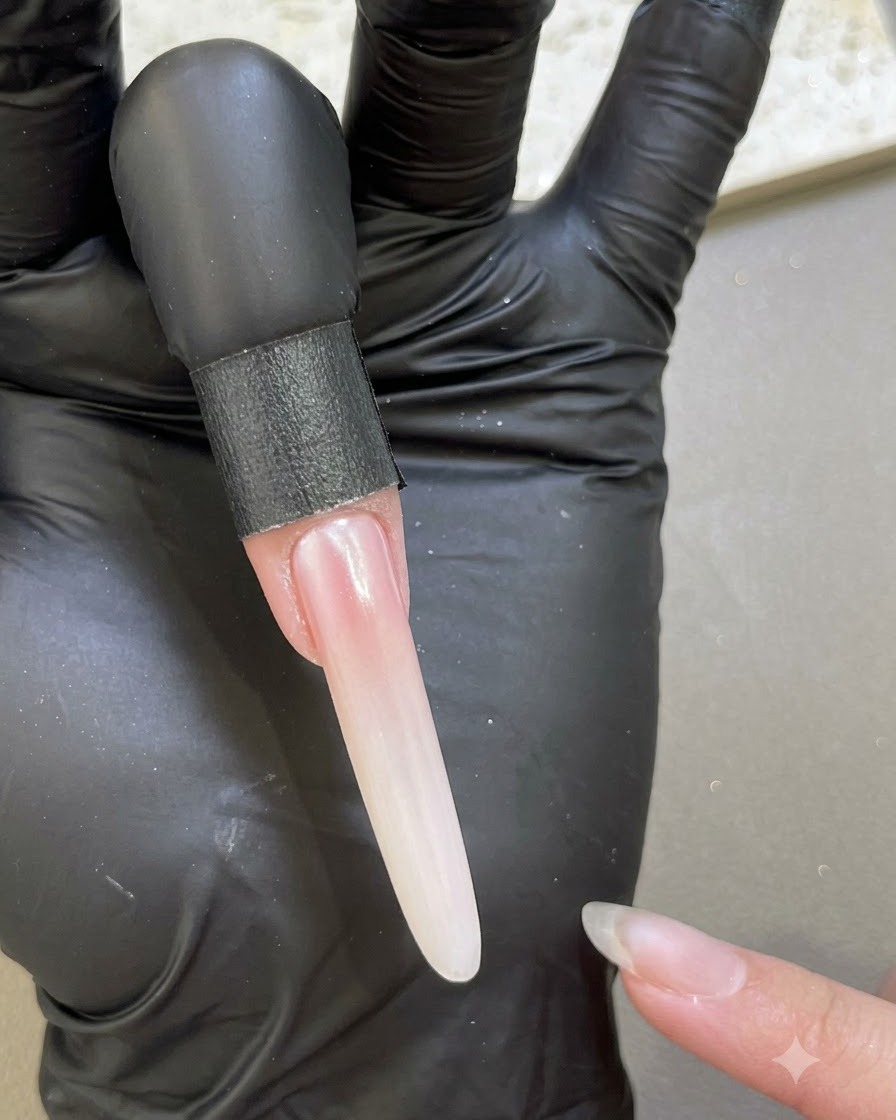 Un ongle rallongé montrant une finition lisse et nacrée après scellement avec le gel de base le long des bords.