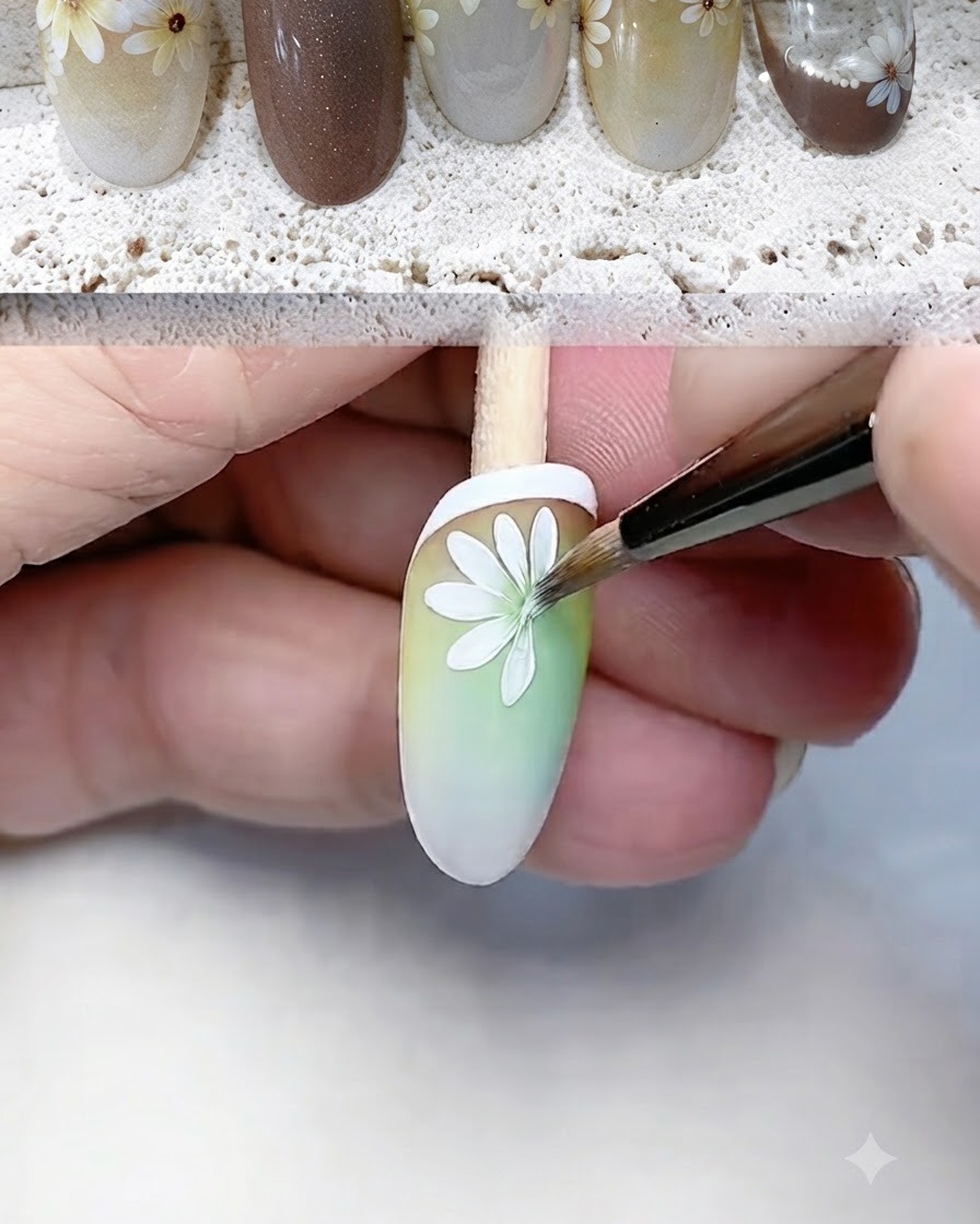 Un pinceau liner fin peignant et définissant avec minutie les pétales blancs de marguerite sur un ongle en dégradé.