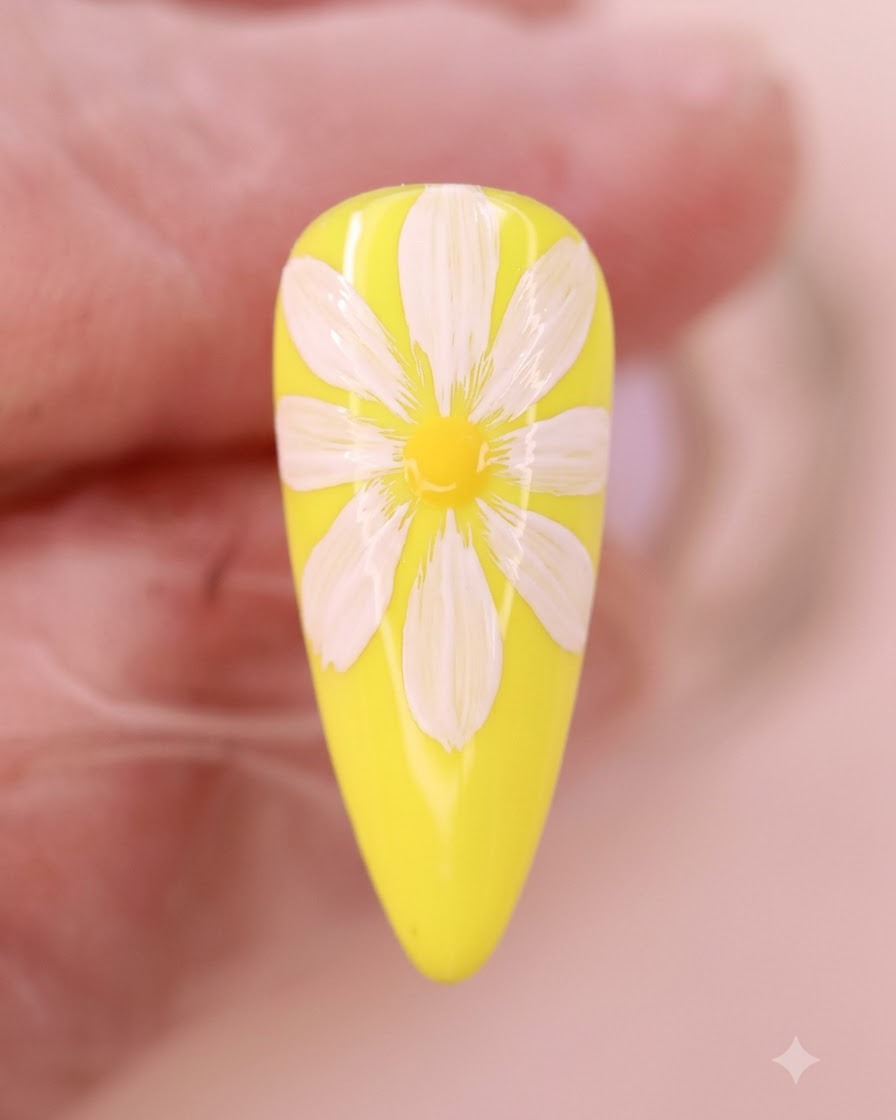 Vue rapprochée de liquide aquarelle jaune diffusant au centre des pétales de marguerite blancs sur un ongle jaune.
