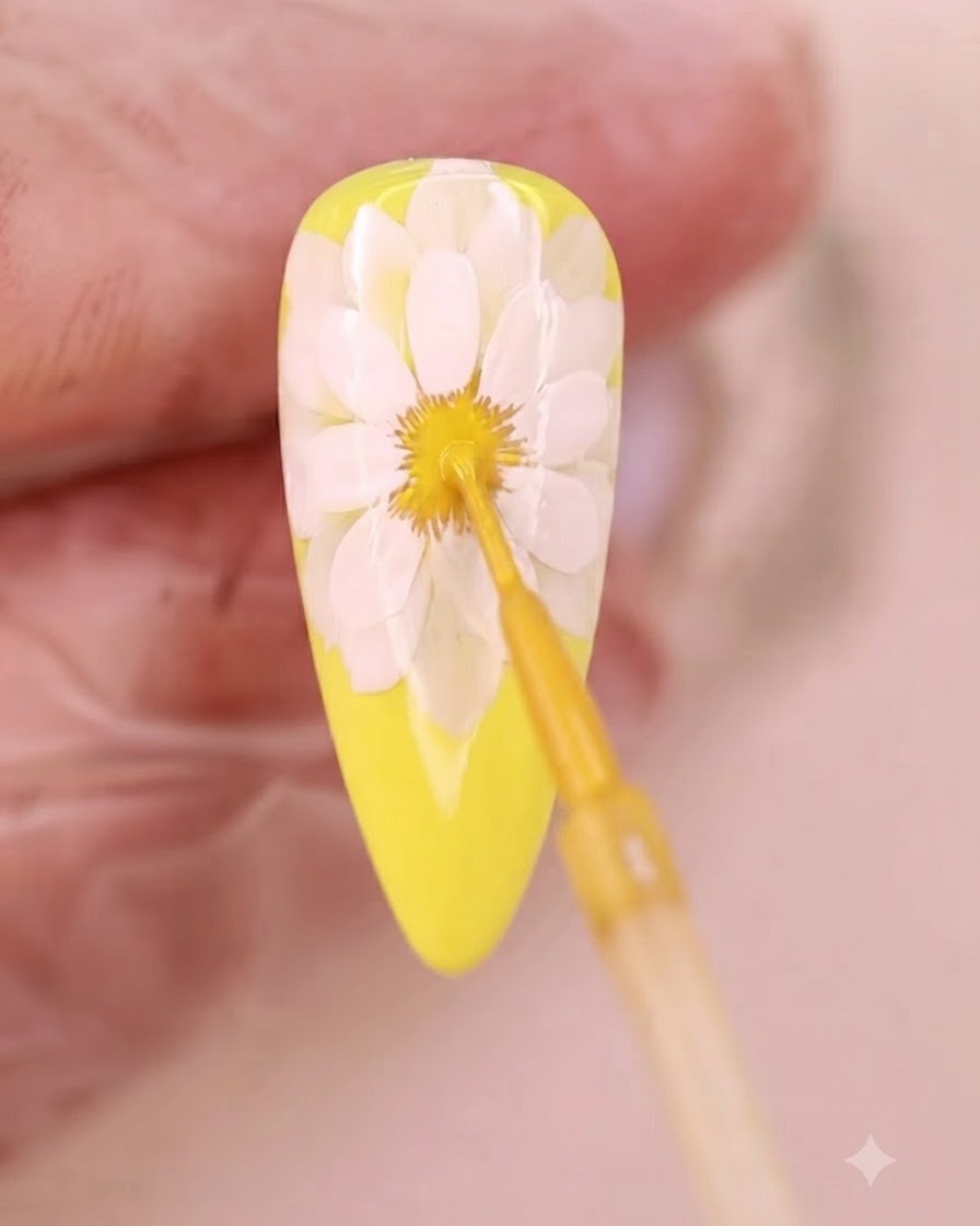 Un pinceau fin appliquant du liquide jaune sur le centre diffus de la fleur.