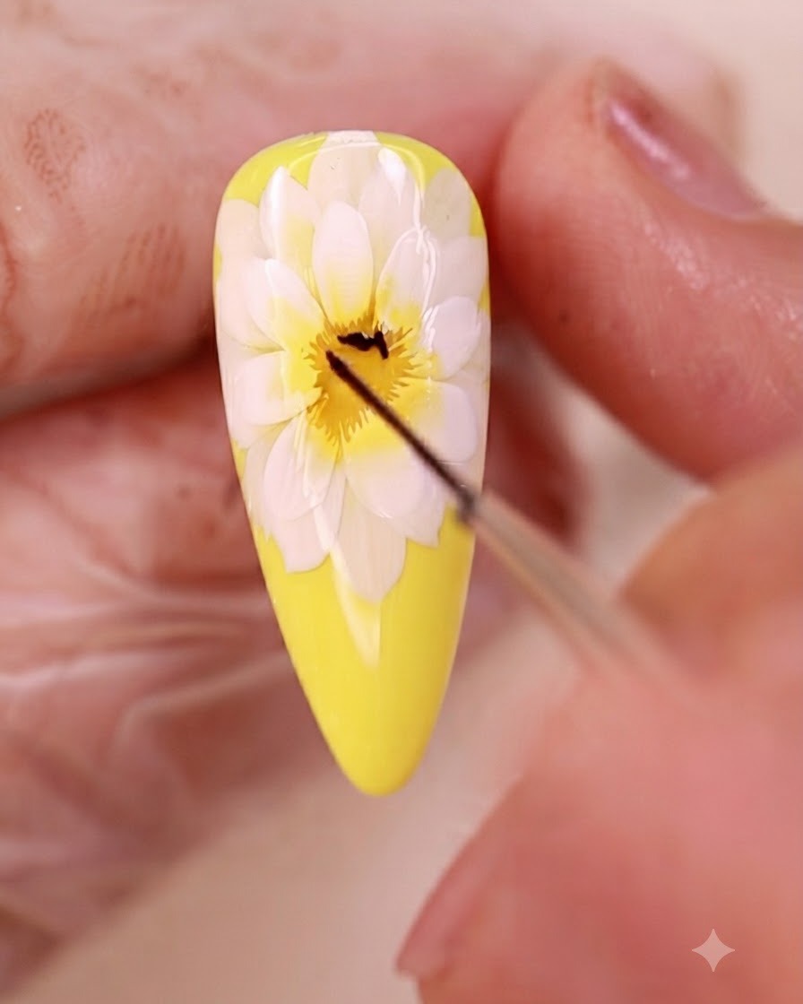 Un pinceau fin liner dessinant de fines lignes noires au centre du nail art floral.