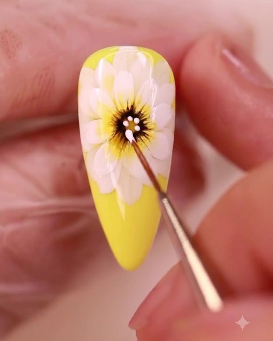 Un pinceau de détail appliquant des points de gel blanc sur le centre sombre dune marguerite jaune peinte.