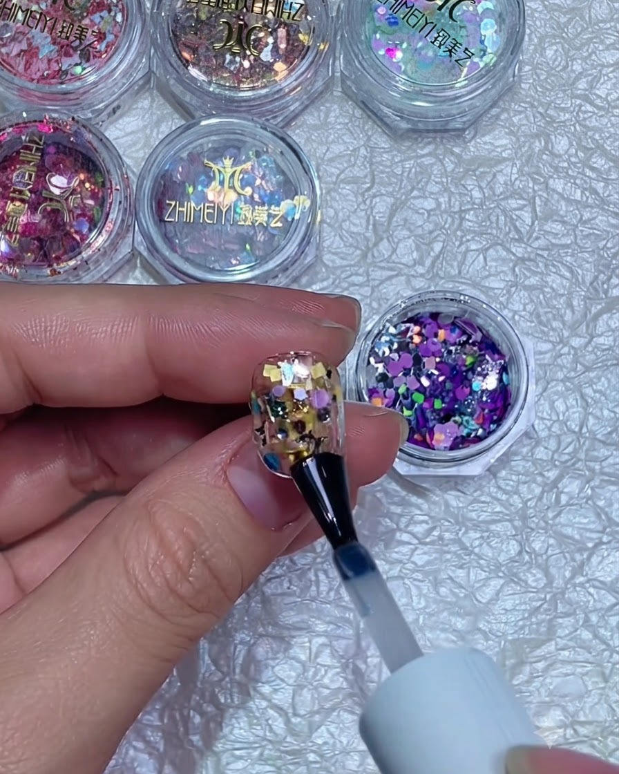 Un bloc polisseur lissant la surface dun ongle encapsulé de paillettes et catalysé.