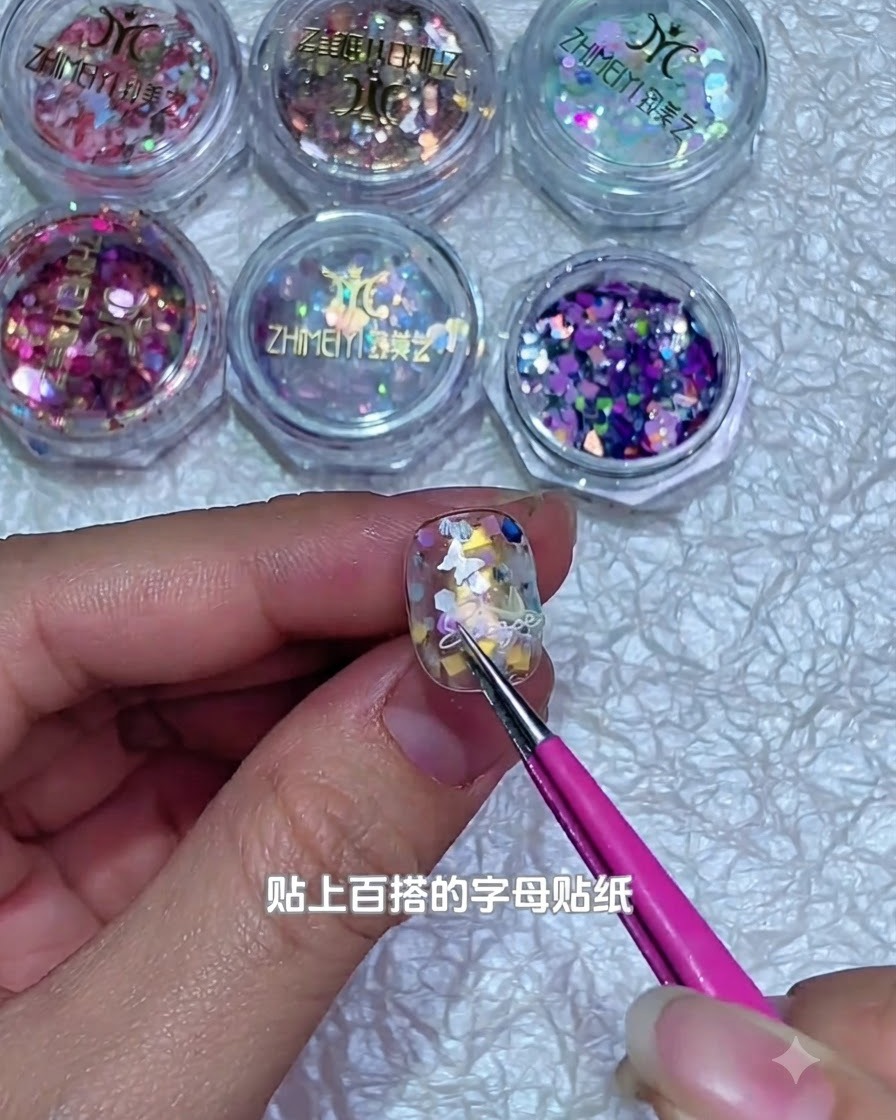 Une paire de pinces posant un minuscule sticker de lettre blanche sur la surface dun ongle en gel décoré.