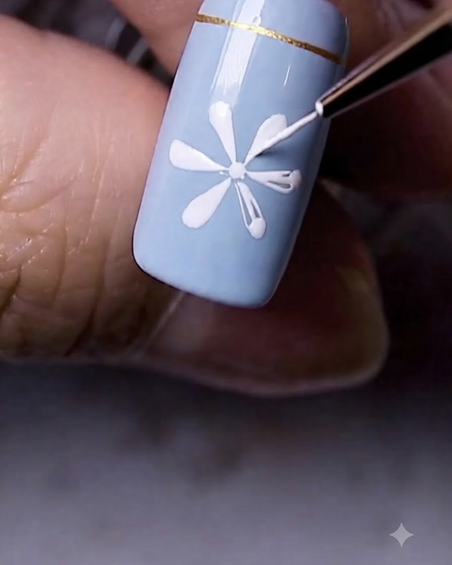 Gros plan dune fleur de marguerite blanche terminée peinte sur la surface dun ongle bleu.