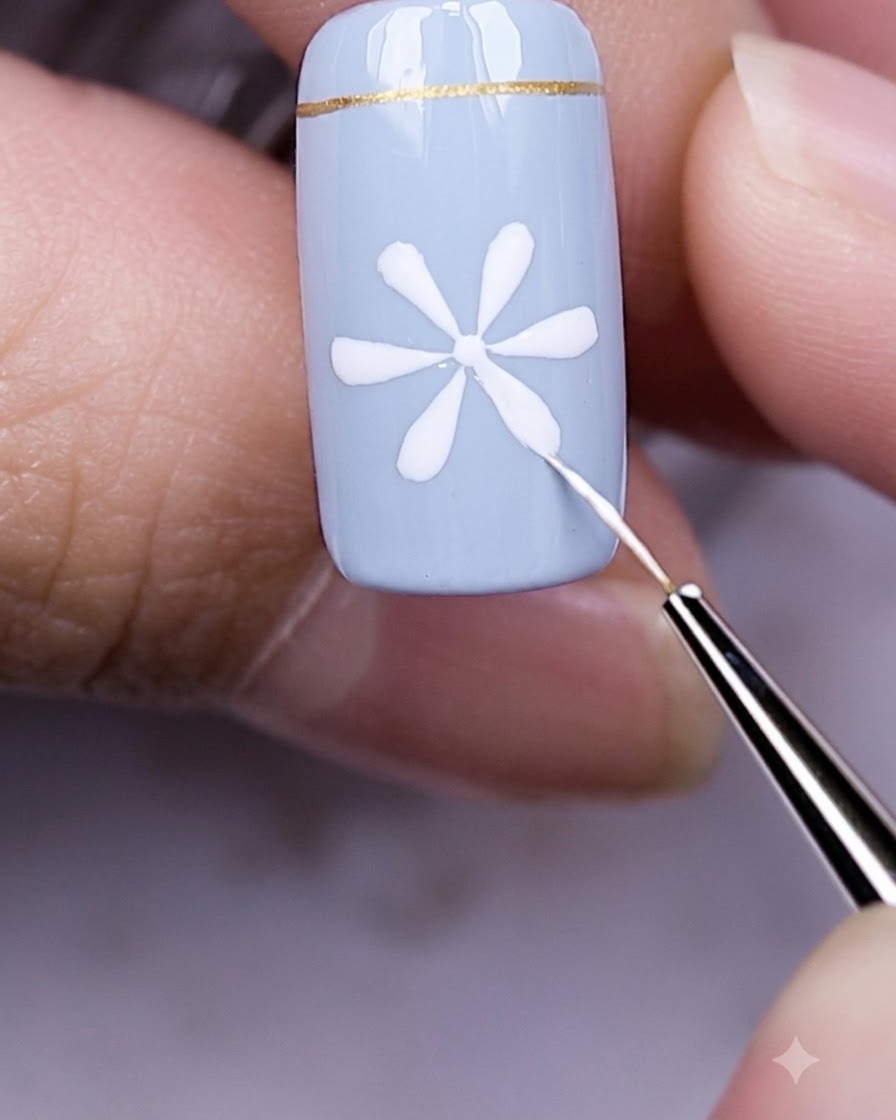 Doigts avec un ongle bleu et un nail art marguerite blanche sous une lampe UV LED allumée.
