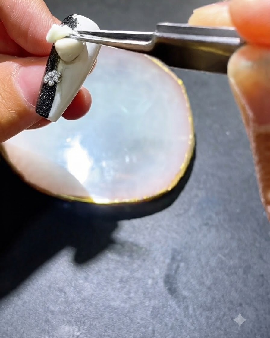 Un outil ou un pinceau appliquant du vernis gel noir sur les côtés dun ongle décoré.