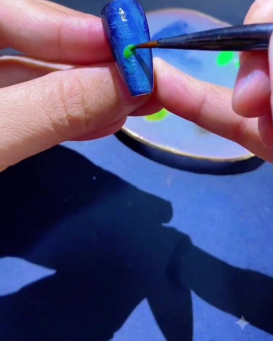 Un pinceau fin appliquant une touche de vernis gel vert sur un ongle texturé bleu.